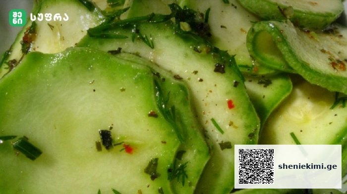Slices of cucumber with chopped dill and seasoning in a light dressing, close-up view of a cucumber salad.