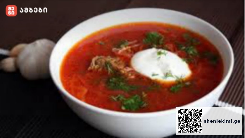Bowl of bright red beet soup (borscht) topped with sour cream and chopped dill; a garlic bulb in the background on the left.