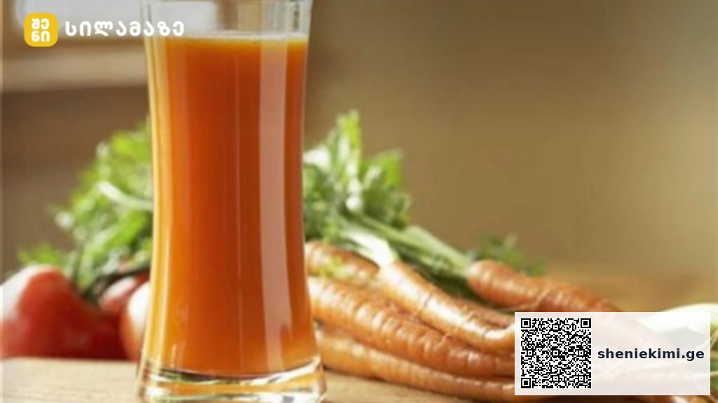 Glass of orange carrot juice on a wooden surface with fresh carrots in the background, suggesting a fresh carrot juice setup