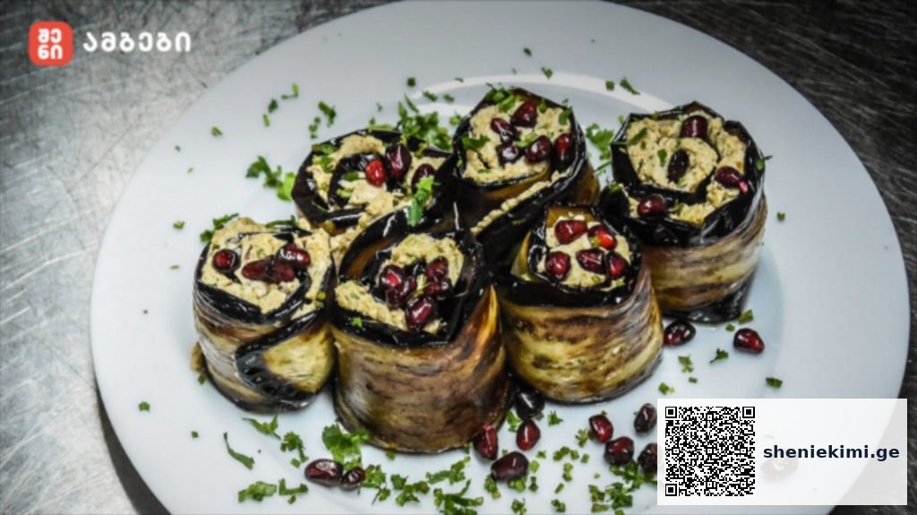 Plate of eggplant rolls filled with a light filling, topped with pomegranate seeds and chopped herbs.