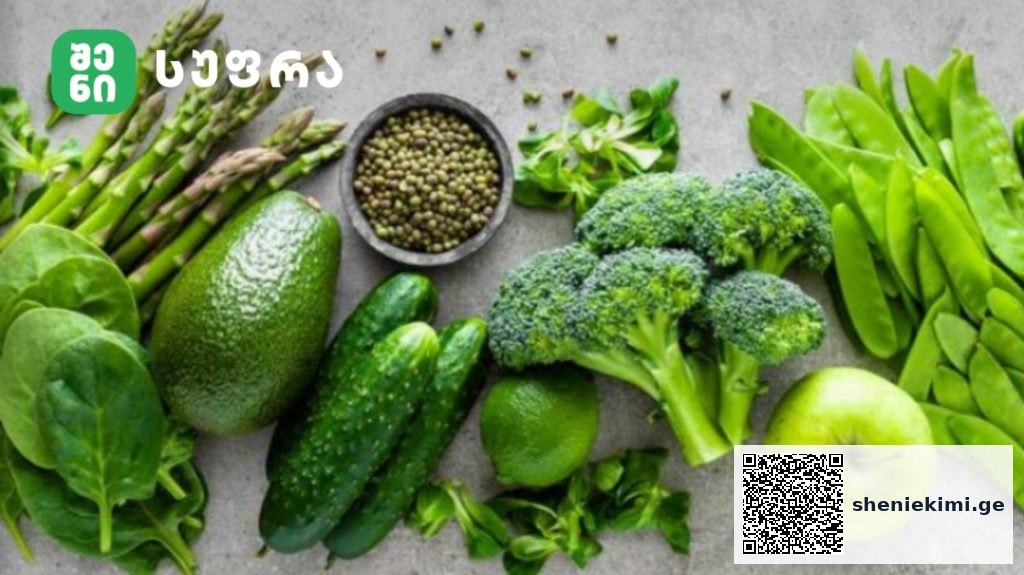 Assortment of fresh green vegetables and a green apple on a gray surface.