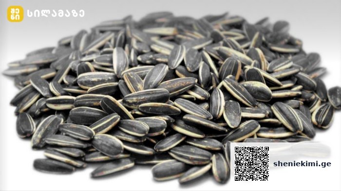 Pile of black striped sunflower seeds on a white surface, arranged in a mound.