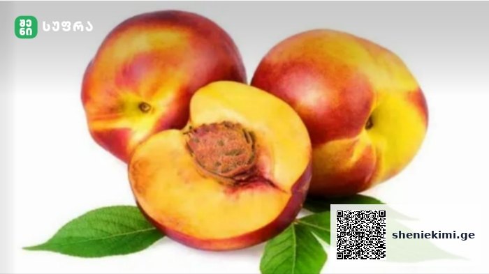 Three ripe peaches, one cut open to reveal the pit, with green leaves on a white gradient background.