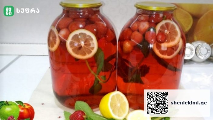 Two large glass jars filled with a red fruit-infused drink with lemon slices and berries, on a white countertop; foreground shows lemons, mint, strawberries, and apples.