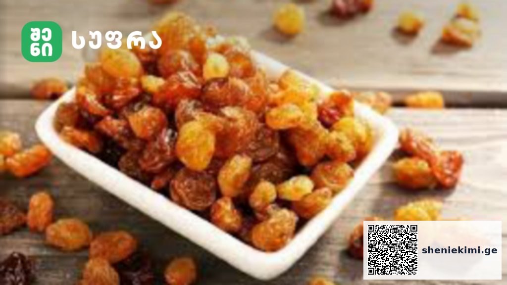 Tray of golden raisins on a wooden surface with a green logo in the top-left corner.