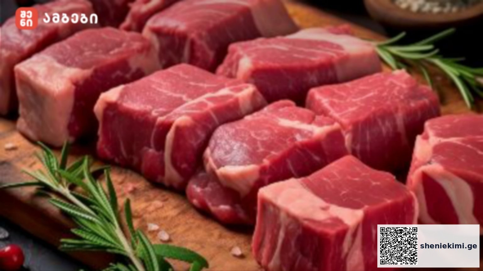 Raw beef cubes with marbling on a wooden cutting board, garnished with rosemary sprigs.