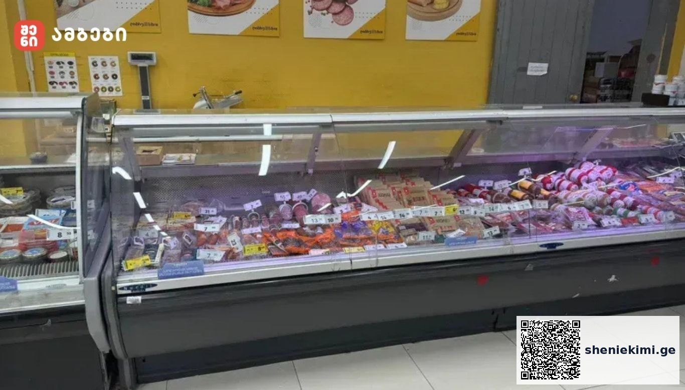 Glass-front deli case filled with assorted sausages and meats on display in a store setting