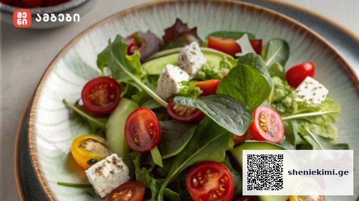 Fresh mixed green salad with cherry tomatoes, cucumber slices, and feta cheese on a plate; logo in the top-left corner.