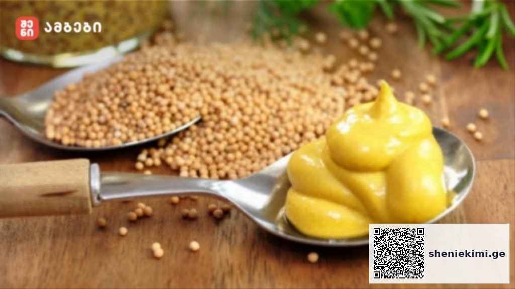 Spoon with swirls of yellow mustard on a metal spoon, with mustard seeds scattered on a wooden surface nearby.