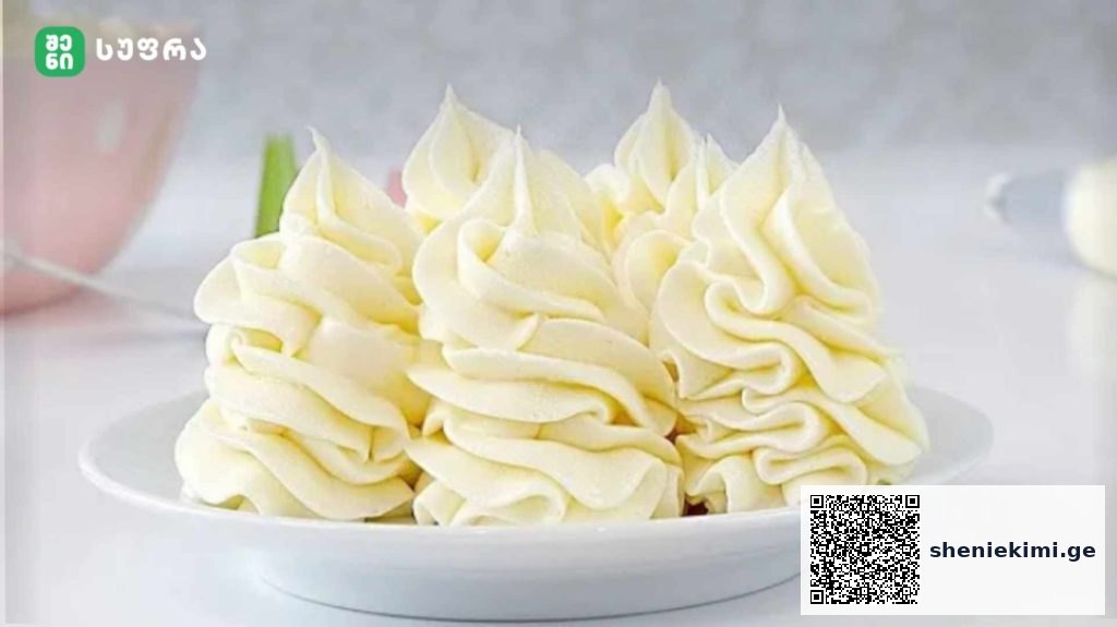 Plate of white buttercream rosettes piped in decorative swirls on a plate