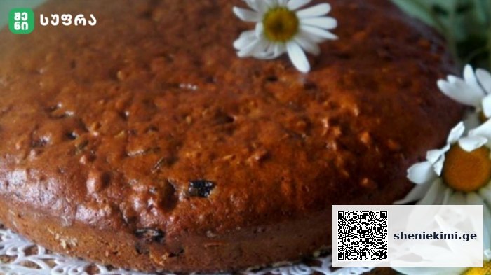 Close-up of a round golden-brown cake on a lace doily, adorned with white daisies.