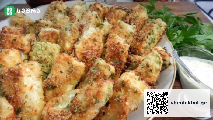 Plate of golden-brown breaded fried pieces with herbs, served with a creamy dipping sauce on the side and parsley garnish.