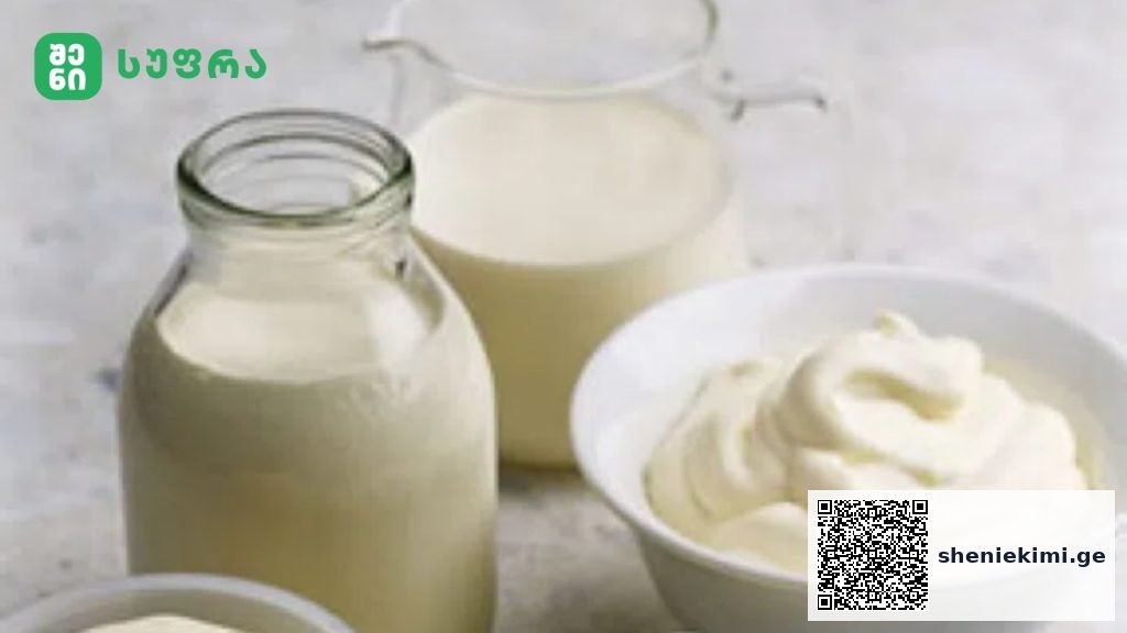 Milk bottles and a pitcher of milk beside a bowl of whipped cream on a light countertop, with a brand logo in the top-left corner.