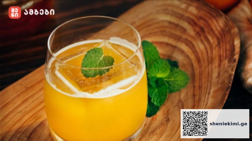 Glass of orange juice with a mint leaf garnish on a wooden board in a rustic setting