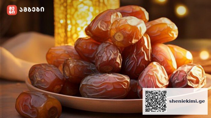 Plate of glossy brown dates piled on a shallow bowl, warm ambient lighting in the background, logo in the top-left corner.
