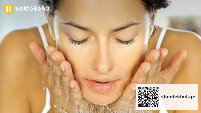 Close-up of a woman rinsing her face with water, cupping water on her cheeks during a skincare routine