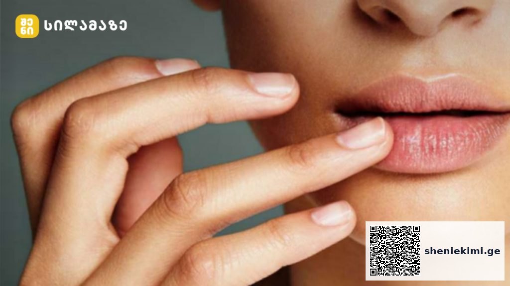 Close-up of a person’s lips with two fingers gently touching the lower lip, logo in the top-left corner