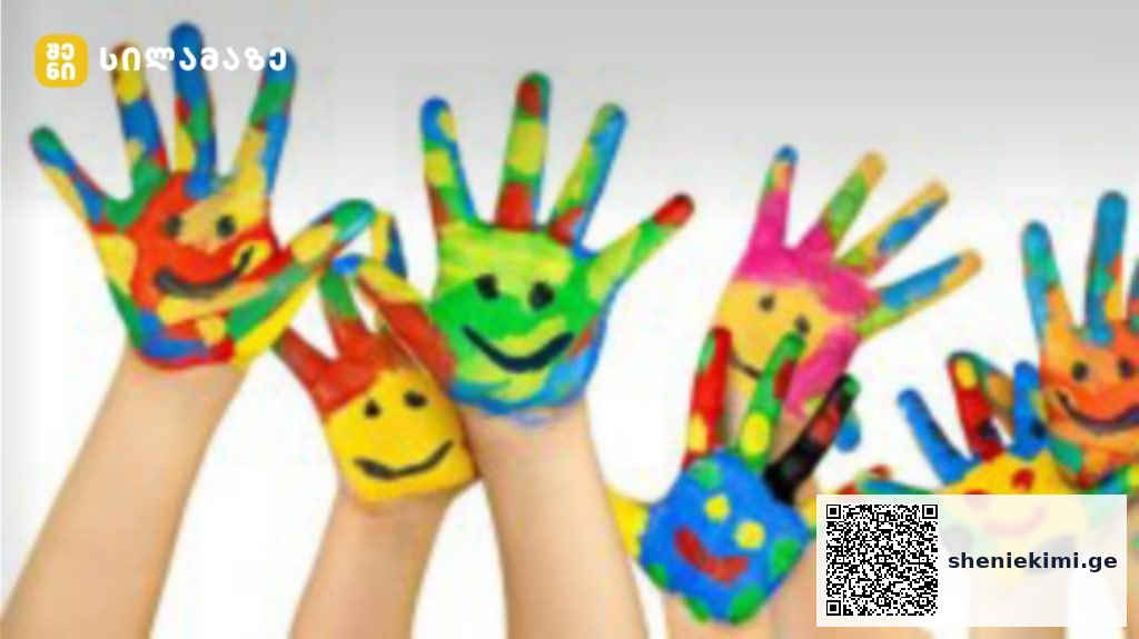 Childrens' hands painted in bright rainbow colors with smiley faces, raised together in a playful art scene.