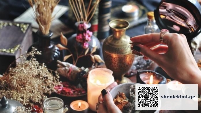Hands arranging dried herbs on a candlelit altar with vases and bowls nearby, creating a ritual scene.