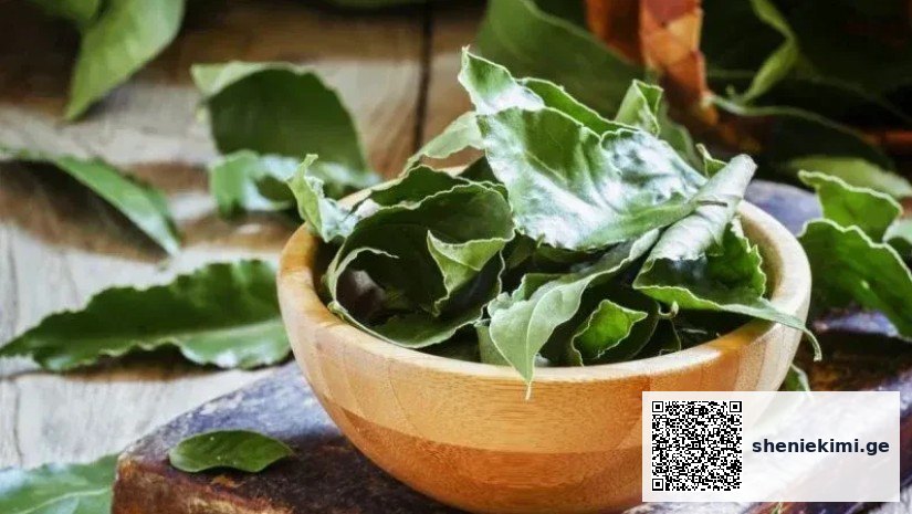 Fresh bay leaves in a wooden bowl resting on a rustic wooden surface.