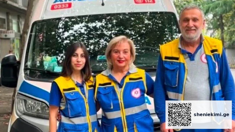 Three emergency responders in blue and yellow uniforms stand in front of a white ambulance with blue markings.