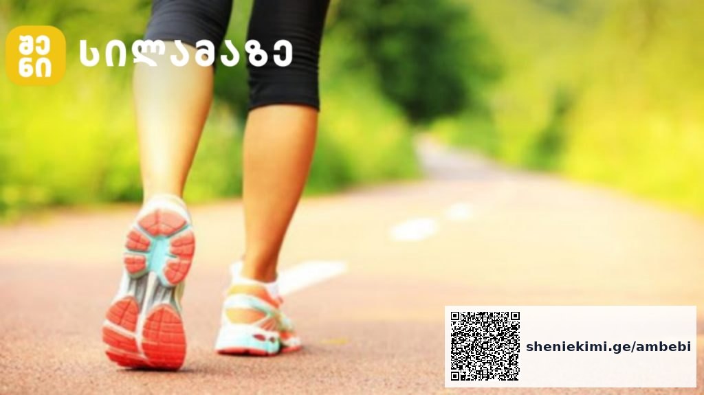 Person's legs in running shoes walking on a sunlit park path; logo appears in the top-left corner.
