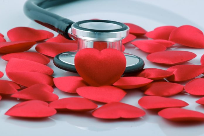Stethoscope nestled among red fabric hearts on a white surface, combining medicine with love.